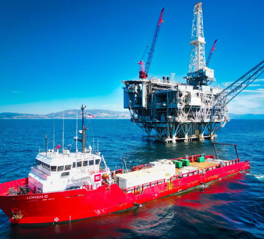 An offshore vessel is pictured, anchored near a fixed offshore platform
