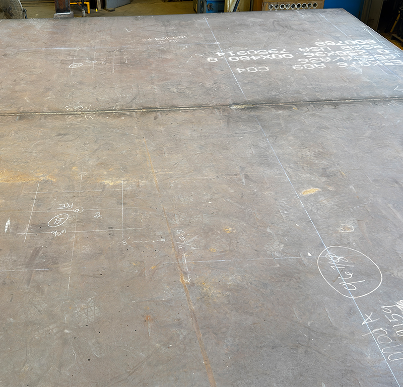 Steel plate with fabrication layout markings used for traceability and offshore module manufacturing.